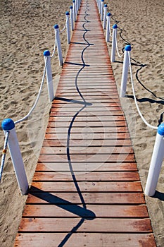 Wooden walkway over the sand dunes to the beach. Beach pathway in Lido di Ostia Lido di Roma, private beach Salvataggio, Italy.