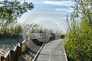 Wooden walkway through the dunes to the Gulf of Riga in Latvia in sunset.