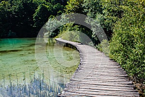 Wooden walkway surrounded with crystal clear water and trees in National Park Plitvice Lakes in Croatia