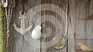Wooden wall decorated by vintage marine accessories, anchor, compass and rope. Shabby old wooden wall and retro nautical