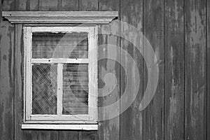 A wooden wall with an old rustic window. The concept of poverty and dilapidation.