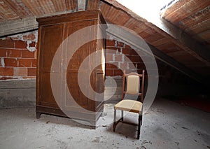 Wooden wardrobe and an antique chair in the dusty attic photo