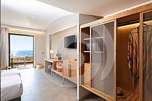 Wooden wardrobe cabinet furniture in white in modern minimalistic style interior of double hotel room with open sea view terrace