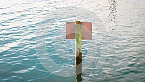 A wooden warning post sticks out of the sea water