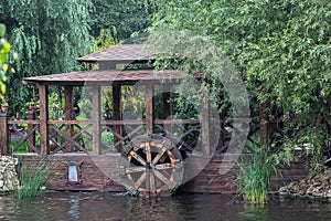 Wooden water wheel on a creek and a small house - mill next to it