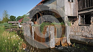 Wooden water wheel of old vintage mill turning water. Mill wheel rotating under stream of water. Old wooden water mill