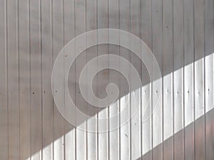 Wooden weatherboard painted white with a wide stripe of sunlight. Background and texture photo