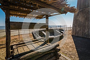 The wooden well, old holey boat on the seashore on a sunny day