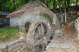 Wooden wheels of an old rural water mill on the slope of a forest hill