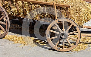 Wooden wheels on an old wagon with hay