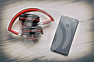 . Wooden white background in the old style. headphones stacked in red. They are cordless and cell phone top view. there is toning
