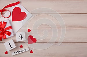 Wooden white background with red hearts, gifts, love envelope and wooden block calendar. The concept of Valentine Day