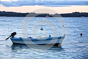 Wooden white and blue boat with black engine on sea