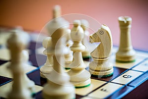 Wooden white chess pieces on a chessboard with a blurred background
