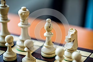 Wooden white chess pieces on a chessboard with a blurred background