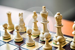 Wooden white chess pieces on a chessboard with a blurred background