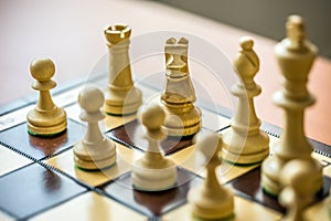 Wooden white chess pieces on a chessboard with a blurred background