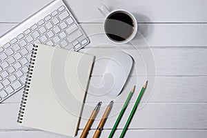 Wooden White office desk table with cup of coffee, Notebook, Pen