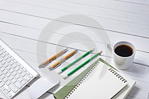 Wooden White office desk table with cup of coffee, Notebook, Pen