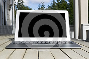 Wooden white office desk table with open blank laptop computer empty space. Front view with copy space. Grey laptop on wooden desk