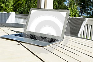 Wooden white office desk table with open blank laptop computer empty space. Front view with copy space. Grey laptop on wooden desk