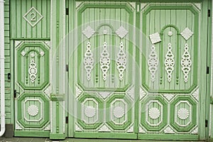 Wooden wide gates in old Russian houses. Figurative ornaments made of wood.Bright colors. Ancient wooden Russian houses.