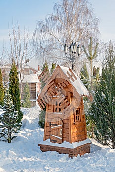 Wooden windmill as a decoration on the street. An old small old wooden mill in the winter garden