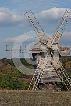 Wooden windmill. Autumnal forest.