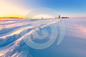 Wooden windmill on background winter sunrise. Dudutki village, Belarus