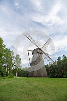 Wooden windmill on green grass field under blue sky