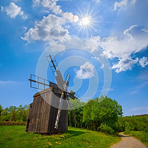 wooden windmill among green rural fields