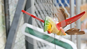 Wooden windmill kinetic sculpture of colorful bird develops in the wind