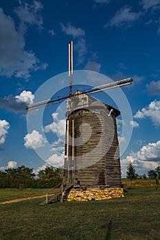 Wooden windmill on rural landscape in sunny summer day