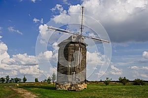 Wooden windmill on rural landscape in sunny summer day