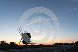 Wooden windmill silhouette by roadside