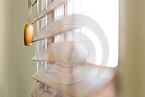 Wooden window blinds partially closed with bright light