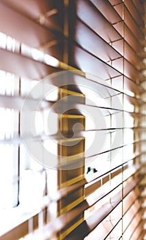 Wooden window blinds partially closed with bright light