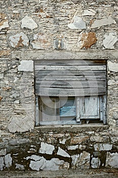 Wooden window boarded on an old rough stone wall farmhouse or ancient house. Vintage, rustic, old fashioned frame and