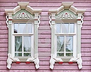Wooden window with carved architraves on pink facade of tatar house early 20th, Kazan, Russia