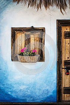 Wooden window with flowers, blue wall and door with padlock, retro style