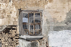 Wooden window on an old crumbling wall with traces of plaster