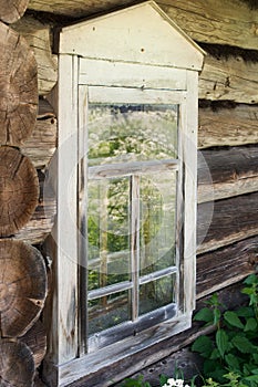 Wooden window in an old log house. The paint exfoliated, worn away from time. Reflection in the glass. Nico did not live