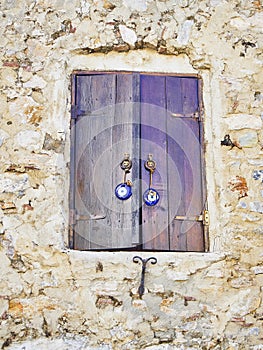 Wooden window on a stone wall with a Nazar boncugu, a Turkish am photo