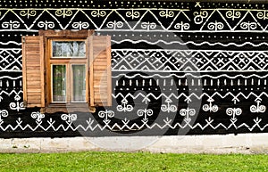 Wooden window on the White and black pattern ornament painting on the dark wood wall in Slovakian old village Cicmany. European