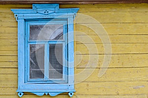 Wooden window on a yellow wooden wall