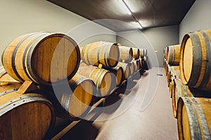 Wooden wine barrels stacked in modern winery cellar in Spain