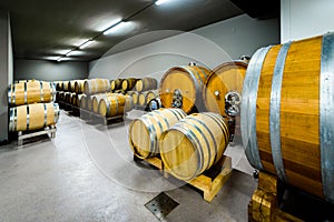 Wooden wine barrels stacked in modern winery cellar in Spain