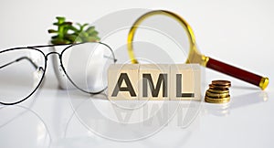 Wooden word block AML on white background with glasses and magnifier