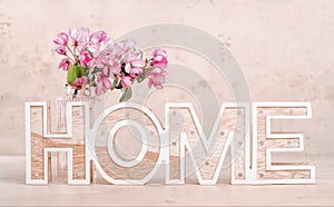 Wooden word home with spring flowers in a vase