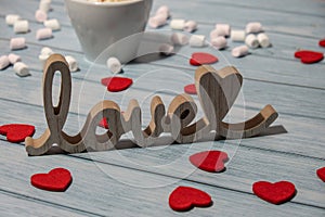 Wooden word love with heart romance with white coffee cup of hot chocolate and small marshmallows. Minimal